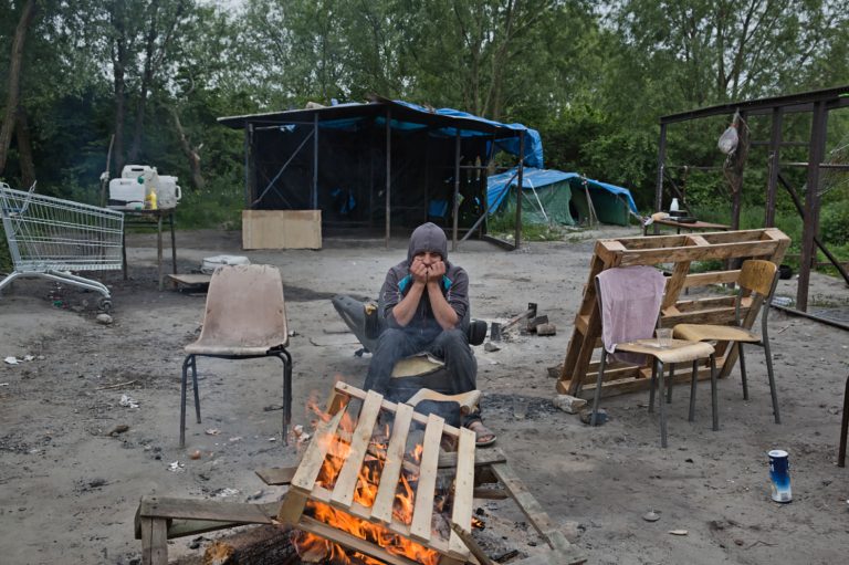 Une personne exilée se réchauffe auprès du feu à Dunkerque, France © Jerome Sessini