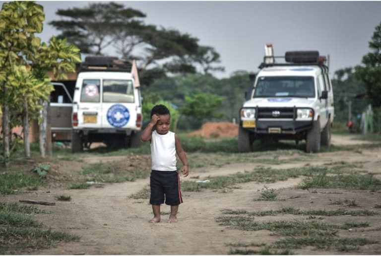 enfant en bas âge sur un terrain avec des camionnettes médecins du monde